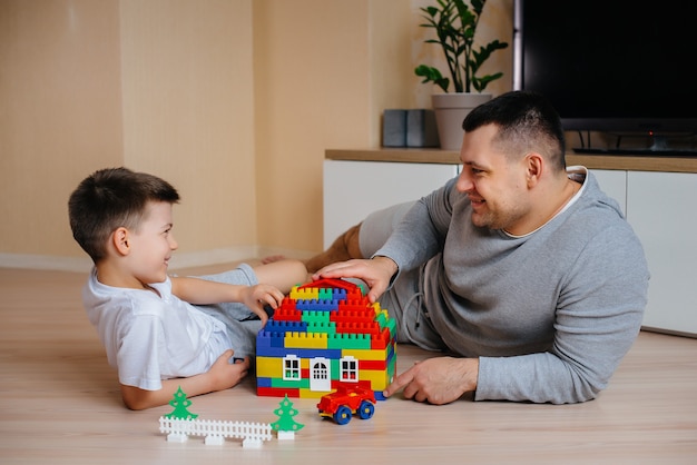 Un petit garçon avec son père est joué par un constructeur et construit une maison. Construction d'une maison familiale.