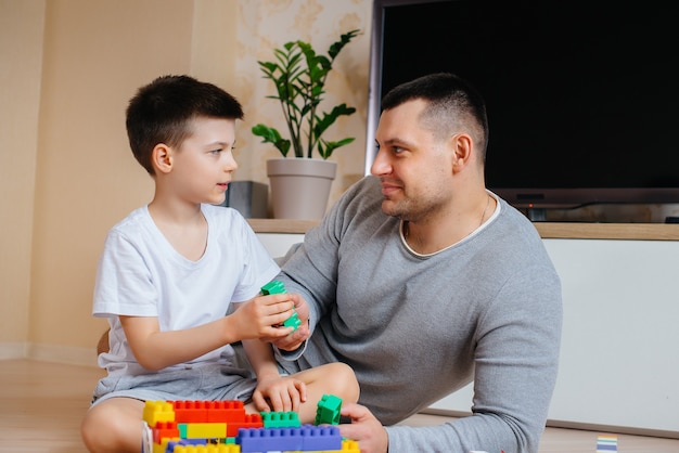 Un petit garçon avec son père est joué par un constructeur et construit une maison. Construction d'une maison familiale.