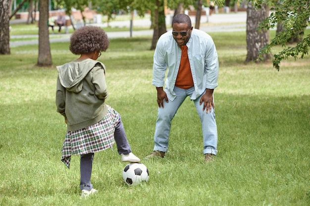 Petit garçon et son père jouant au football sur pelouse verte