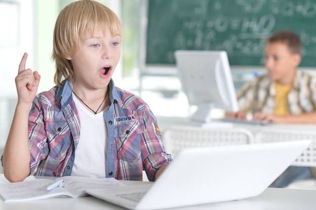 Petit garçon souriant dans la salle de classe, son camarade de classe en arrière-plan