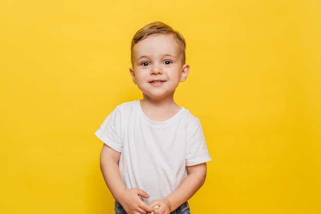 Petit garçon souriant sur fond jaune. Espace de copie.