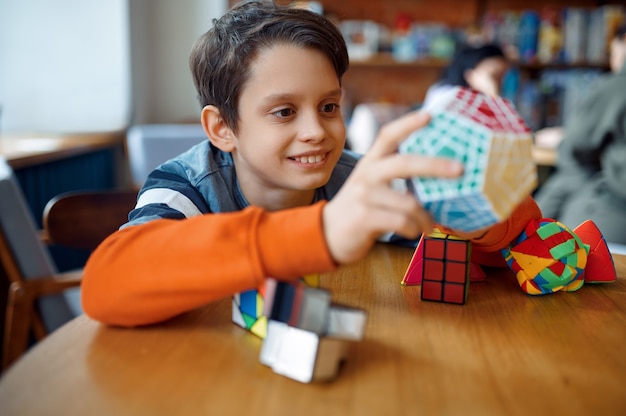 Un petit garçon souriant joue avec des cubes de puzzle colorés. Jouet pour l'entraînement du cerveau et de l'esprit logique, jeu créatif, résolution de problèmes complexes