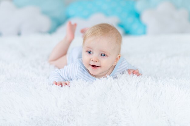 Un petit garçon souriant sur le lit se couche ou se réveille le matin