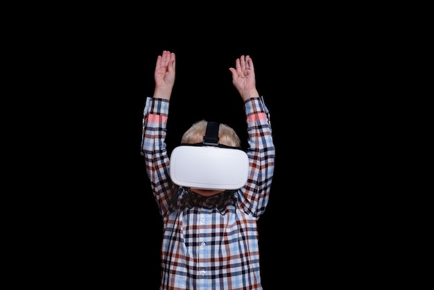 Petit garçon souriant avec des lunettes de réalité virtuelle avec les mains levées