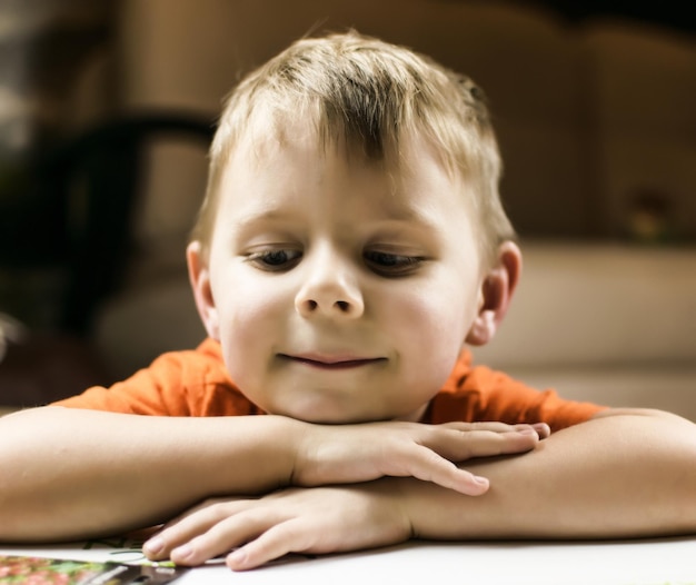 Le petit garçon sourit et repose son visage sur ses mains