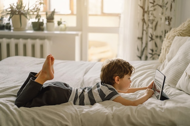 Photo petit garçon avec une tablette dans la chambre