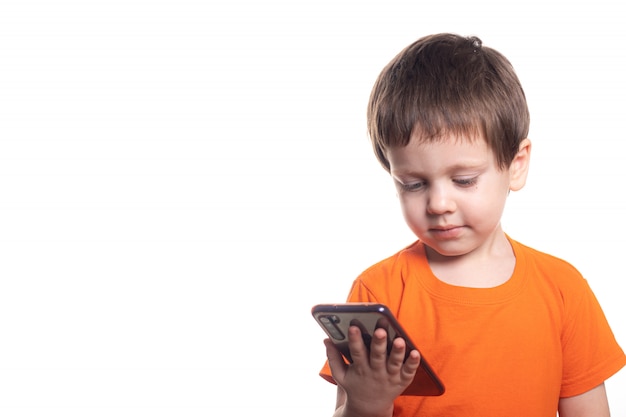 Un petit garçon avec un téléphone sur fond blanc. Téléphone garçons