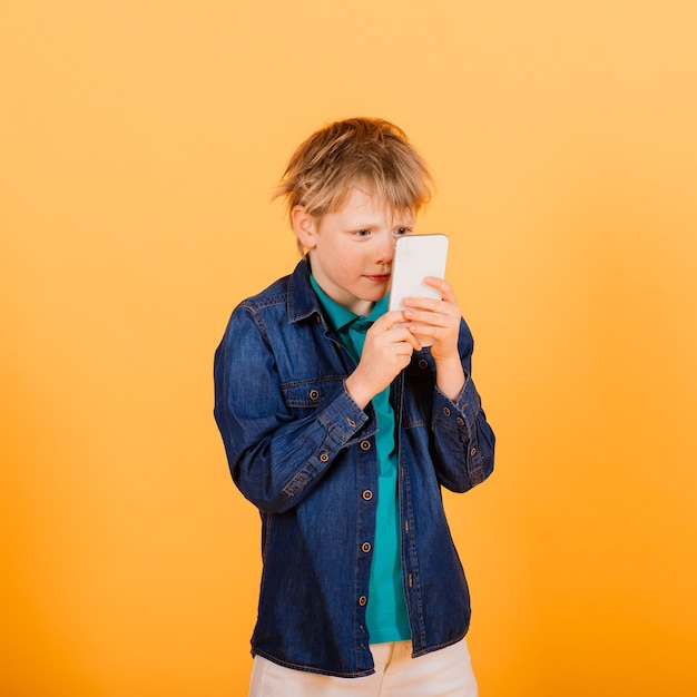 Le petit garçon téléphone sur le mur jaune