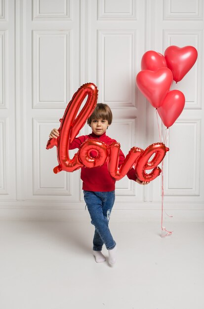 Petit Garçon Tenant Un Ballon D'amour Sur Fond Blanc Avec Des Coeurs De Ballons