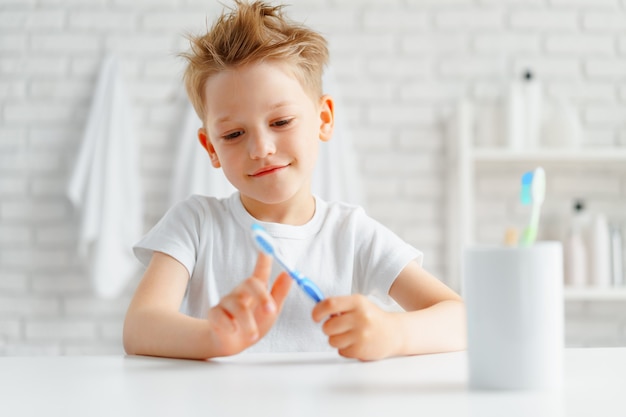 Petit garçon tenant une brosse à dents dans sa main debout dans la salle de bain