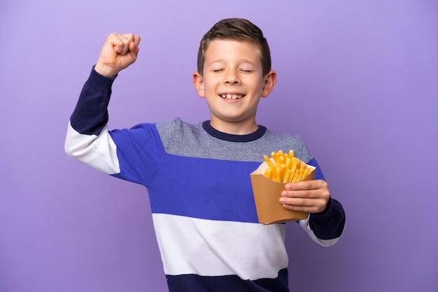 Petit garçon tenant des frites frites isolées sur fond violet faisant un geste fort