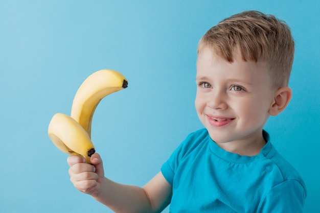 Petit garçon tenant et mangeant une banane