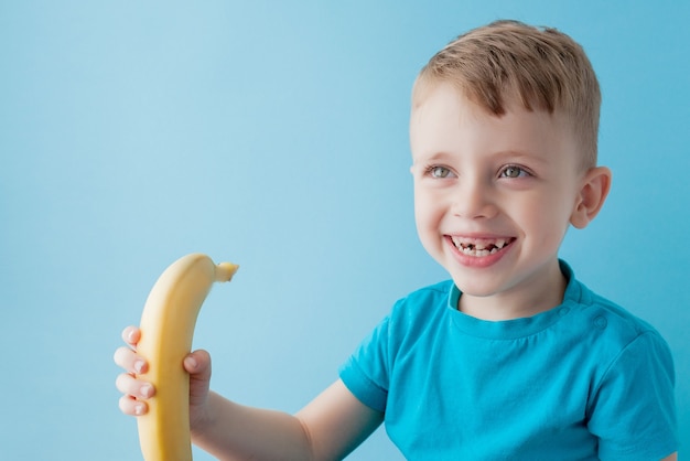 Petit garçon tenant et mangeant une banane