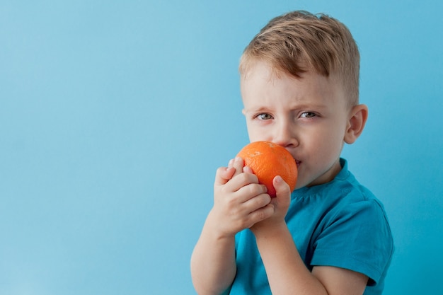 Petit garçon tenant une orange dans ses mains