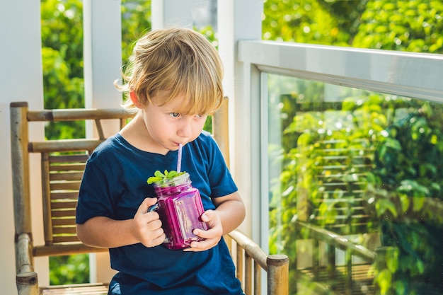 Petit garçon tenant un verre de smoothie