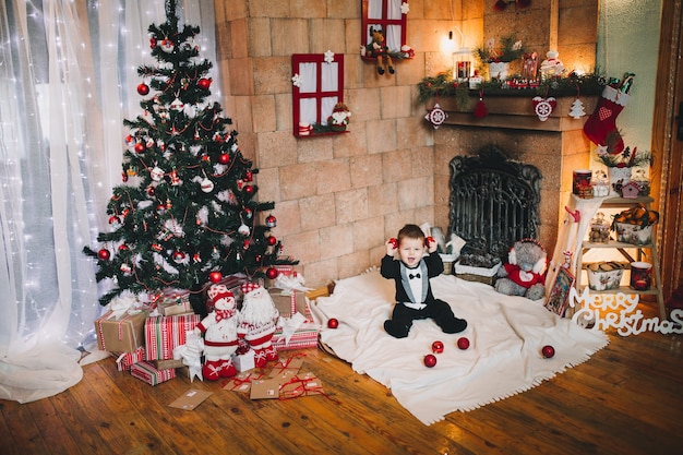 petit garçon tient une balle jouet sur l'arbre de Noël