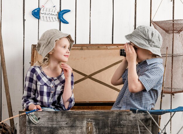 Photo un petit garçon tire sur une petite fille dans une grande poitrine.