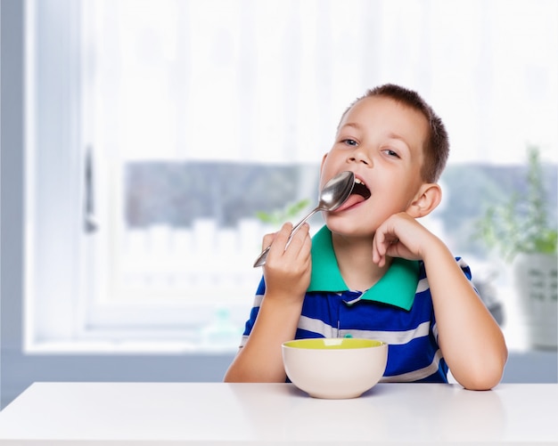 Petit garçon en train de manger un petit déjeuner sain dans la cuisine