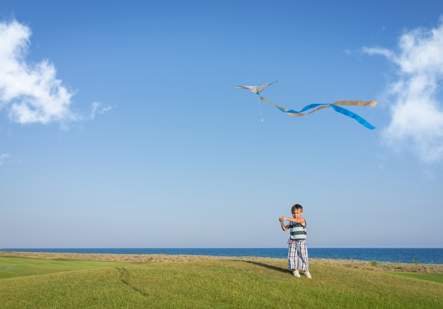 Petit garçon sur les vacances d&#39;été s&#39;amuser et heureux temps voler cerf-volant sur la plage de la mer