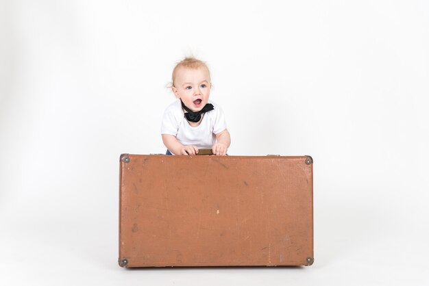 Petit garçon avec la valise sur l'espace blanc