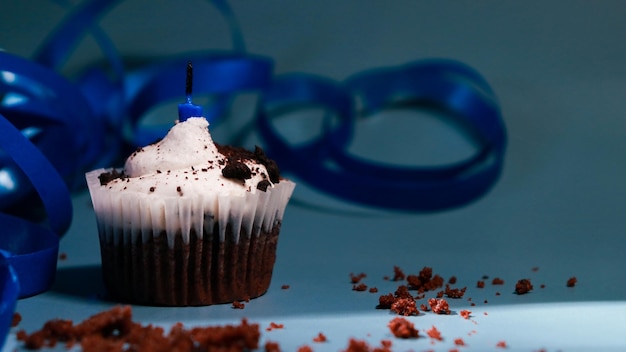 petit gâteau au chocolat avec une bougie bleue, un fond bleu et un ruban bleu