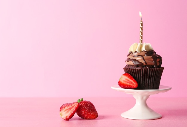 Petit gâteau au chocolat savoureux avec des baies sur fond rose