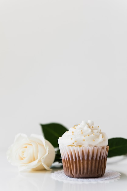 Petit gâteau à la crème fouettée avec rose blanche isolé sur fond blanc