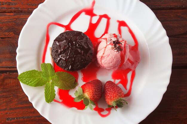 Petit gateau à la crème glacée sur une assiette blanche à la fraise sur une table en bois rustique