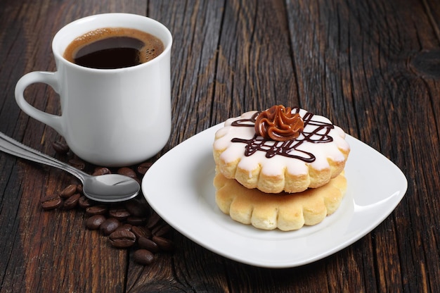 Petit gâteau rond avec crème au chocolat et tasse de café sur une table en bois foncé