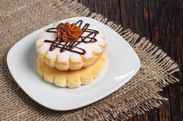 Petit gâteau rond avec glaçage et crème au chocolat sur table en bois foncé