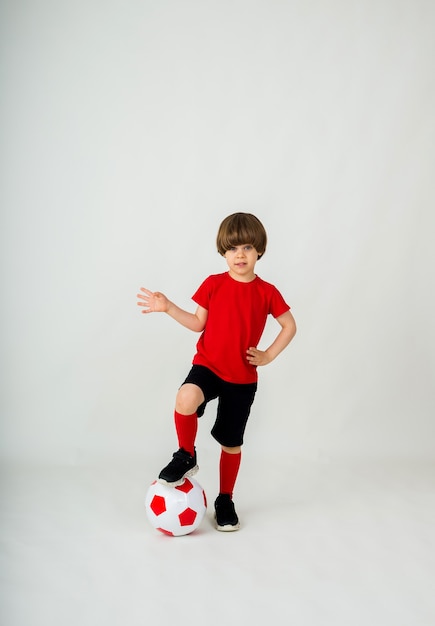 Petit joueur de football se tient avec un ballon de football sur un mur blanc avec un espace pour le texte