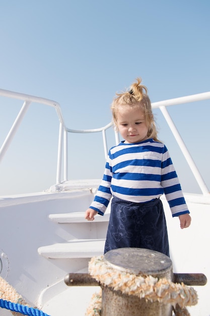 Petit marin enfant sur bateau enfant drôle en chemise marine rayée voyage aventures et envie de voyager vacances d'été enfance heureux petit garçon enfant sur yacht voyage en bateau par mer ou océan mode enfant