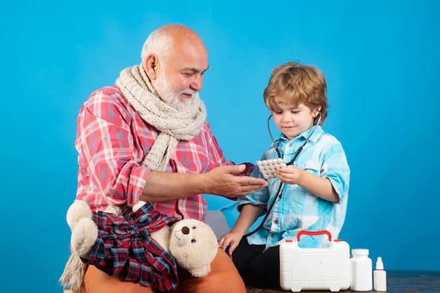 Petit médecin à l'aide d'un stéthoscope vérifiant le patient Médecin enfant souriant et vieil homme patient sur fond de couleur
