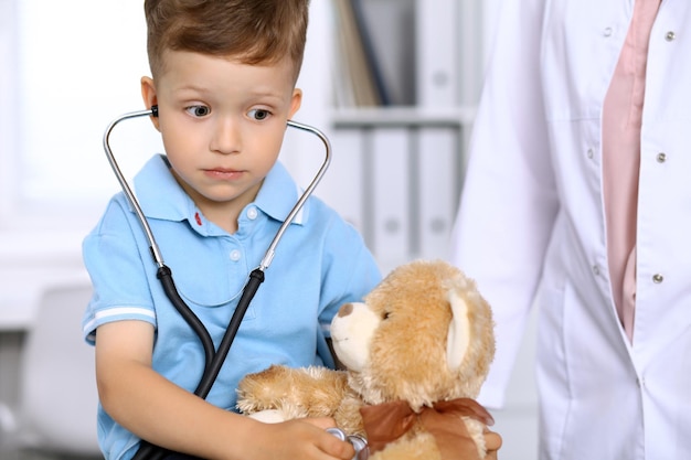 Petit médecin examinant un patient ours en peluche par stéthoscope