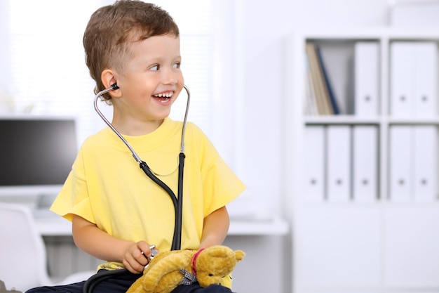 Petit médecin examinant un patient ours en peluche par stéthoscope