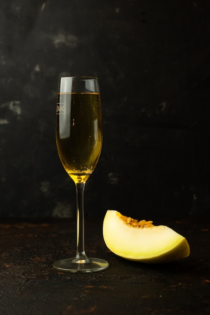 Petit melon jaune juteux avec une coupe de champagne sur la table