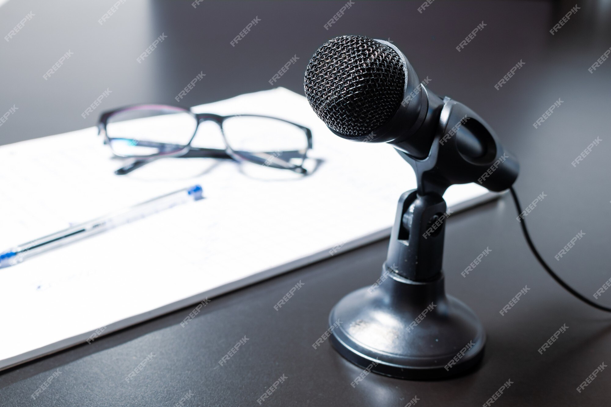 Petit Microphone De Bureau Noir Avec Câble Et Support Bas Sur Une Table  Noire à Côté Du Bloc-notes, Des Lunettes Et Des Lunettes