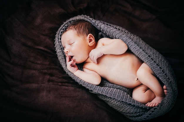 Un petit nouveau-né se trouve sur un plaid marron