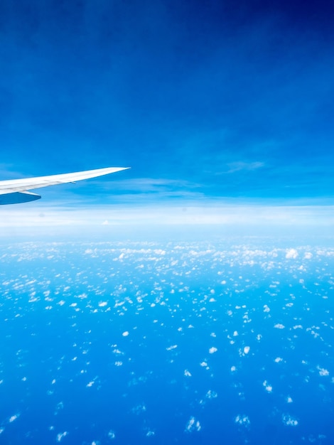 Petit nuage gonflé sur ciel bleu avec aile d'avion depuis la vue de la fenêtre de l'avion