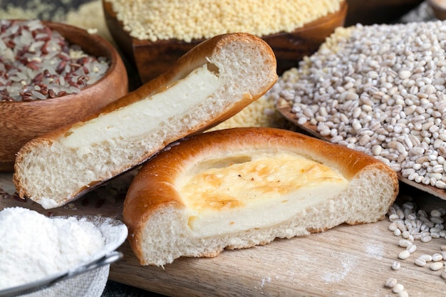 Un petit pain à l'aide de crème sure sur une planche à découper avec de la nourriture à base de grains d'orge perlé sur la table