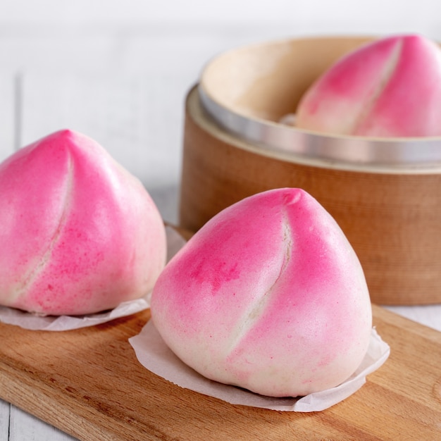 Petit pain d'anniversaire pêche chinois rose nommé shoutao sur fond de tableau blanc.