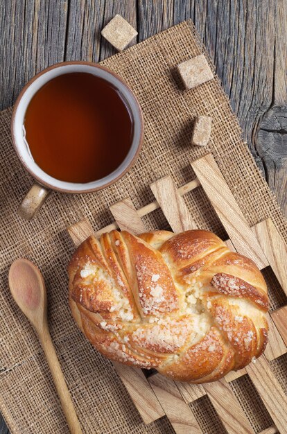 Petit pain en osier sucré et tasse de thé sur la table