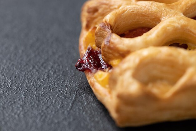 Petit pain sucré avec de la confiture de cerises sur fond sombre