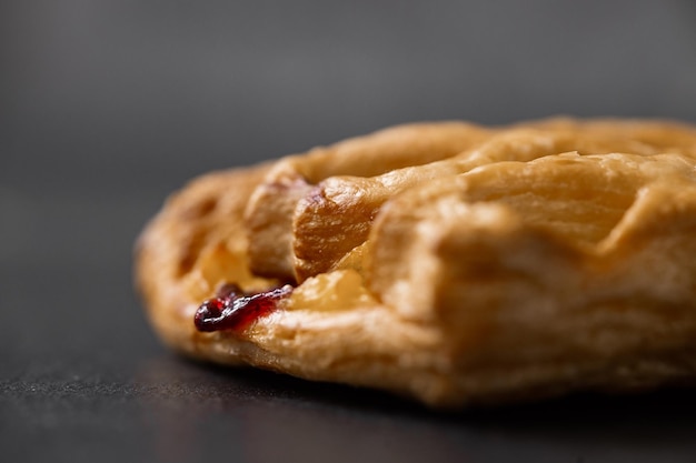 Petit pain sucré avec de la confiture de cerises sur fond sombre