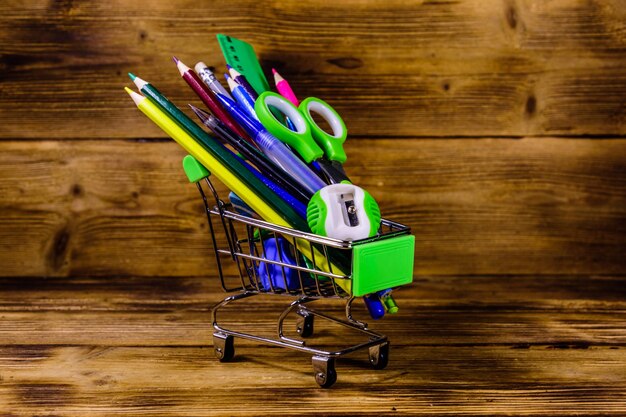 Petit panier avec différents articles de papeterie scolaire sur un fond en bois Concept de retour à l'école