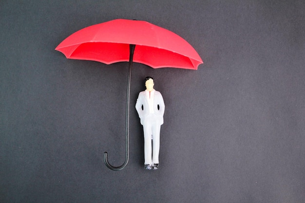 Un petit personnage avec un parapluie rouge sur fond noir.