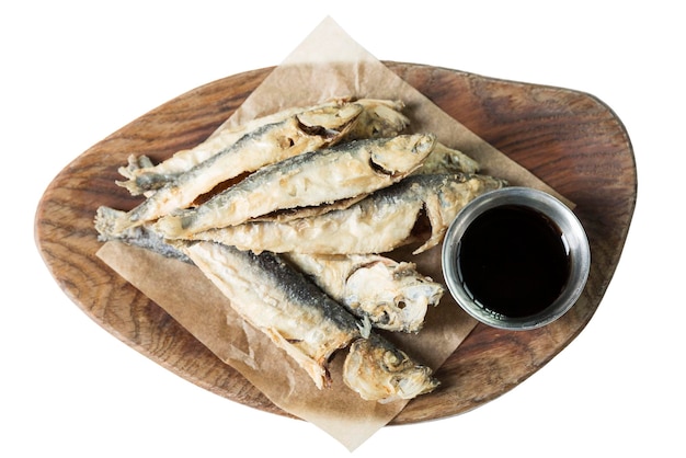 Petit poisson pané frit avec sauce servi sur une planche de bois Apéritif savoureux traditionnel Isolé sur fond blanc Vue de dessus