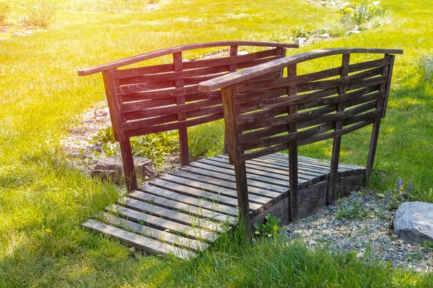 petit pont en bois dans un beau jardin verdoyant.