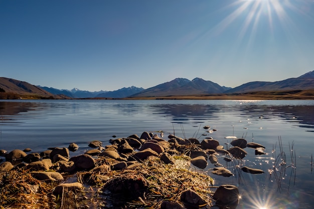 Petit promontoire rocheux menant au lac calme avec les Alpes du Sud