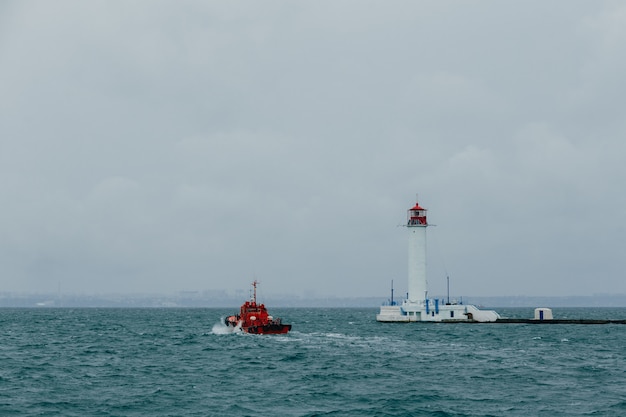 Photo un petit remorqueur rouge nage devant le phare du port